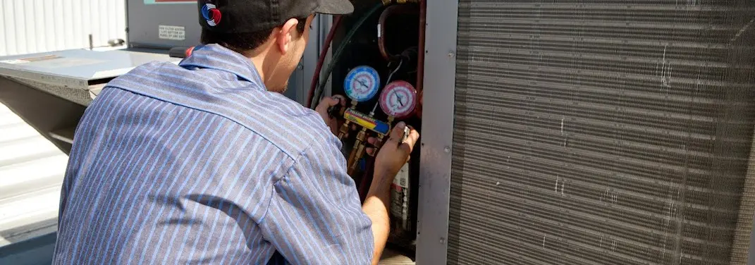 HVAC technician servicing a condenser unit in Shawnee